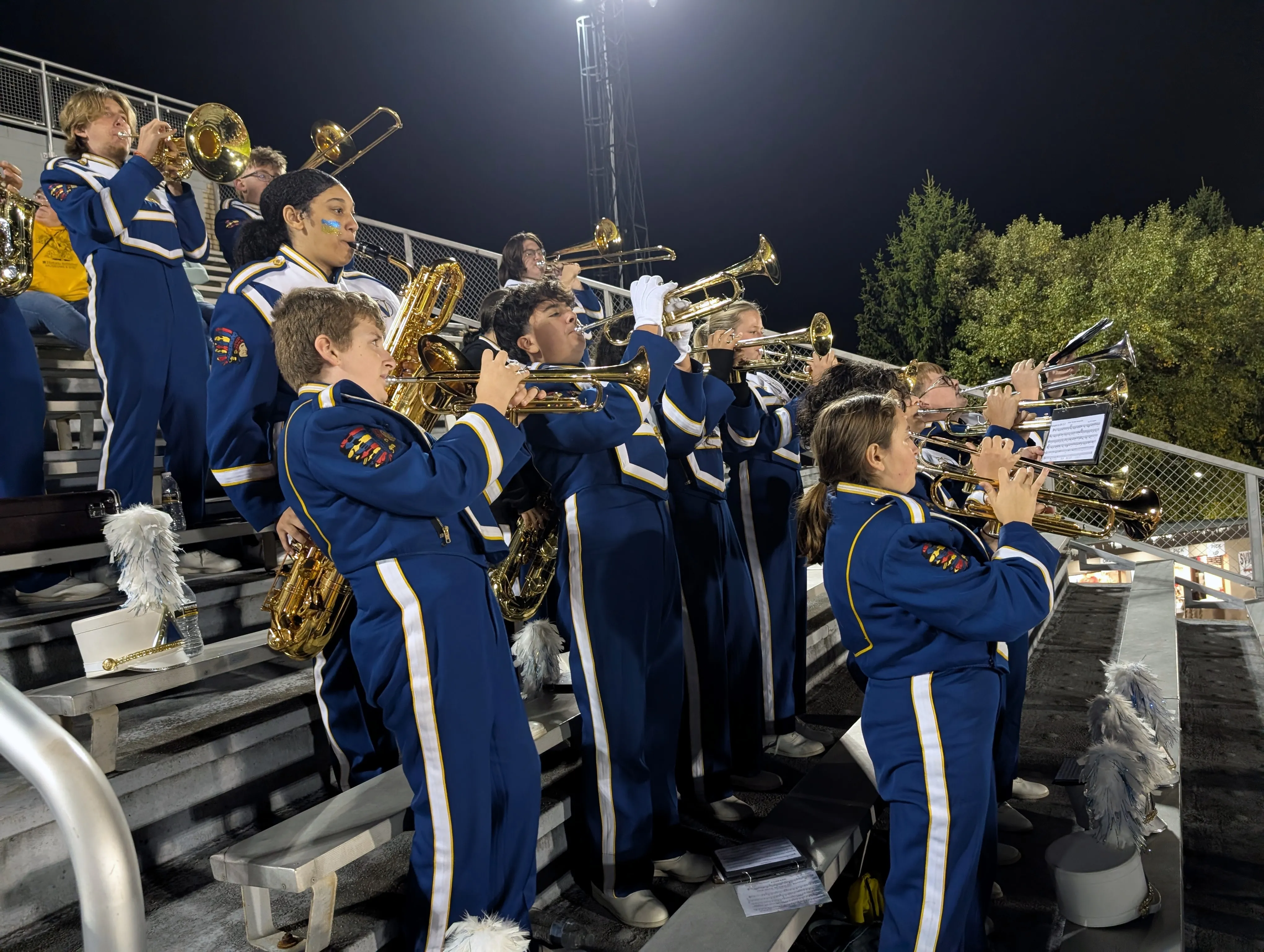 The brass section playing in the stands at a night game